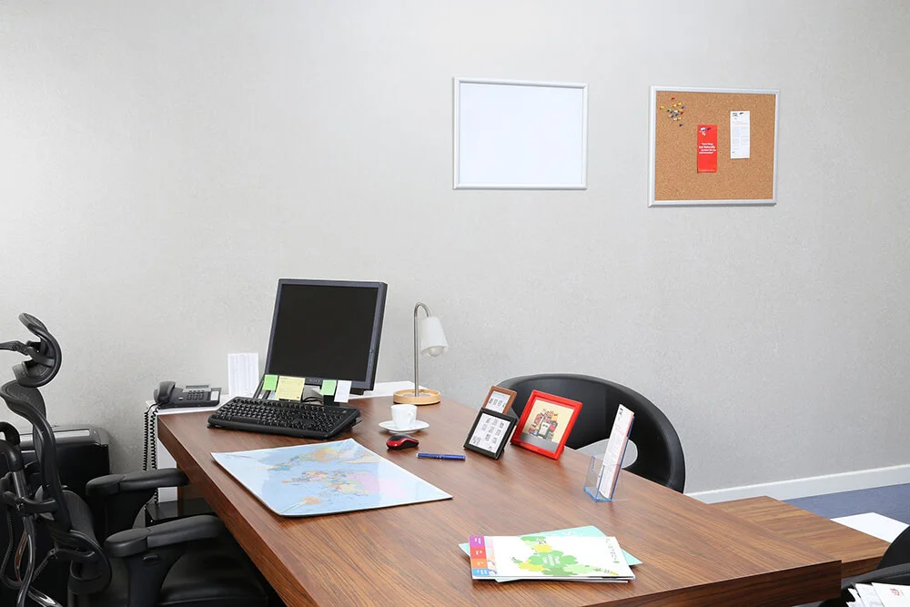 opti-frame-5-x-7-055-red-ral Desk with Computer, papers and frames on it.