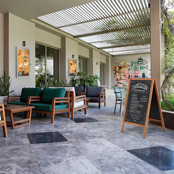 An outdoor seating area with a chalkboard A-Frame board as well as artwork hung in locking poster show boards