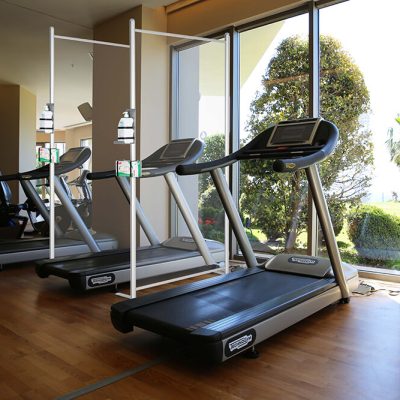 Treadmills facing a window with clear wall separators between them with a locking show board with fliers in it on the wall