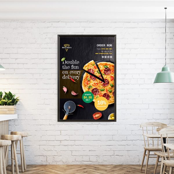 A pizza advertisement hung in a snap poster frame on a white brick wall in a small cafe