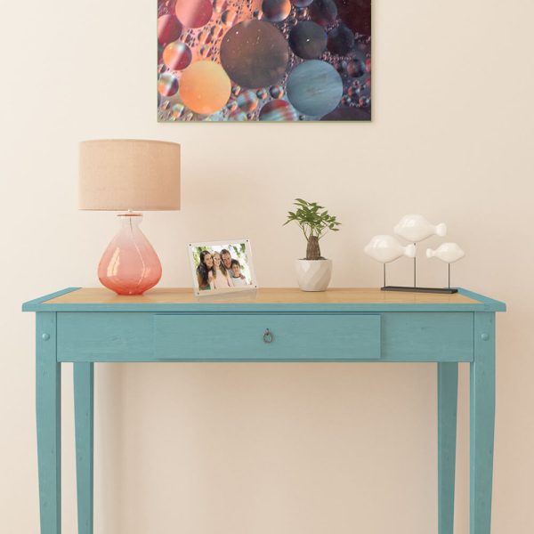 entry way table with art hanging above it with a lamp, plant, decor and a family photo on it