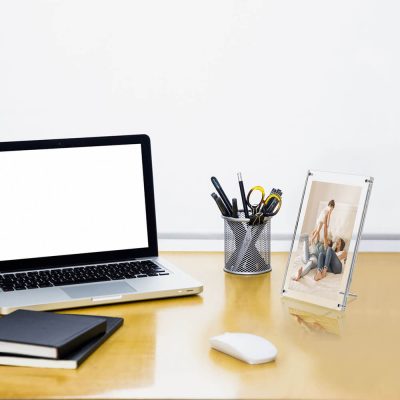 desk with a pen holder, laptop, notebooks, and a family photo in an acrylic sign frame