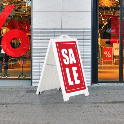 Sale sign on a white SignPro Sidewalk sign outside of a clothing store