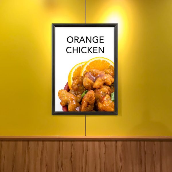 A poster depicting orange chicken in a snap poster frame on a yellow wall in a restaurant