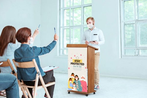 Man giving a speech to a very eager crowd behind a wooden podium