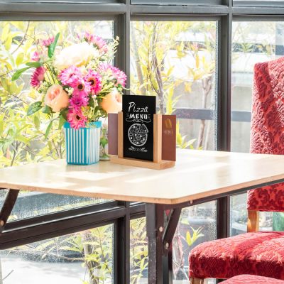 Desk top menu holder next to a bouquet of flowers in a small cafe