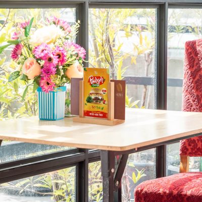 Desk top menu holder next to a bouquet of flowers in a small cafe