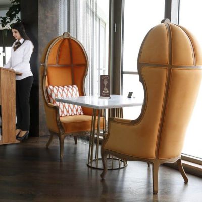 Woman Speaking behind a plywood stand up podium in a fancy restaurant