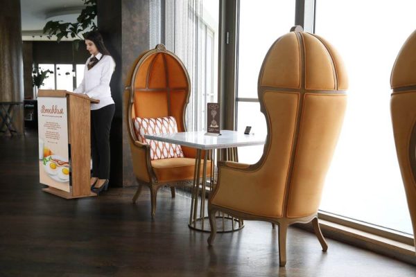 Woman Speaking behind a plywood stand up podium in a fancy restaurant