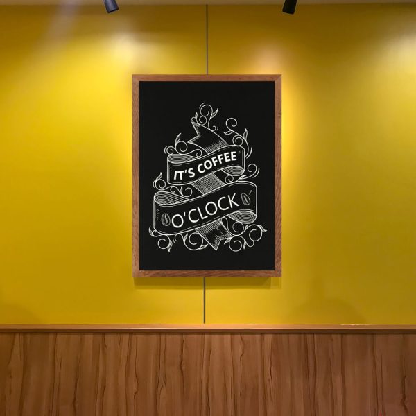 Coffee quote written on a framed chalkboard hanging on a yellow wall in a coffee shop