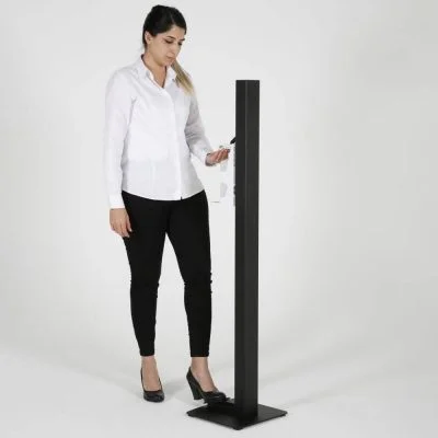 A woman getting hand sanitizer from the black touchless hand sanitizer dispenser with foot pedal