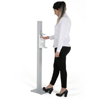 Woman dressed in business clothes using the Touchless hand sanitizer dispenser.