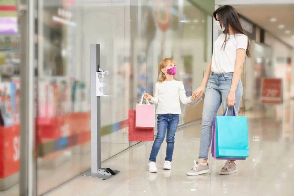 Gray Touchless Hand Sanitizer Dispenser in a mall with a mother and her daughter walking next to it