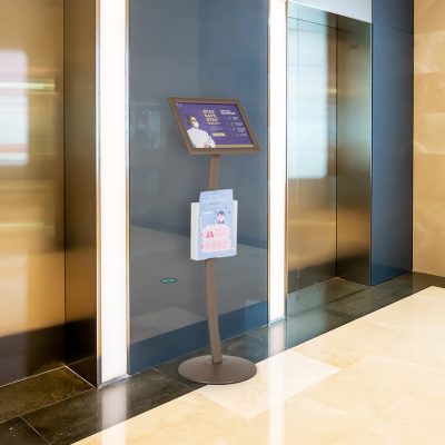 Pedestal sign holder between two elevators