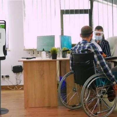 Man in a wheelchair checking in with his female coworker about some files.