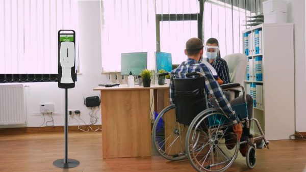Man in a wheelchair checking in with his female coworker about some files.