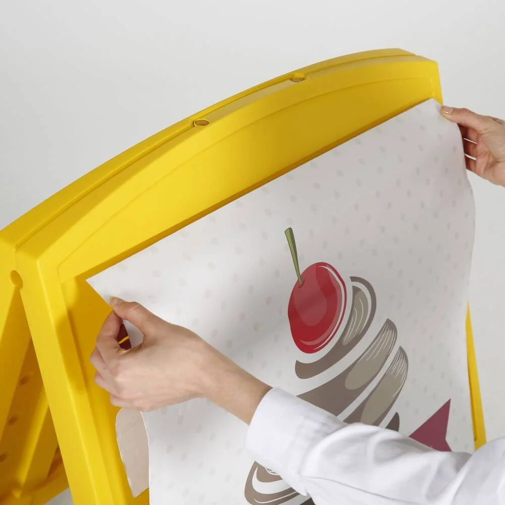 sandwich-board-a-frame-double-sided-outdoor-sidewalk-sign-holder-24-80x19-76-yellow (7) a woman placing a sticker poster on the sandwich board a-frame double sided outdoor sidewalk sign holder