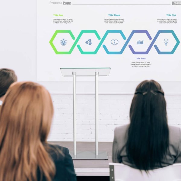 Women sitting in a class, looking at a podium and the presentation