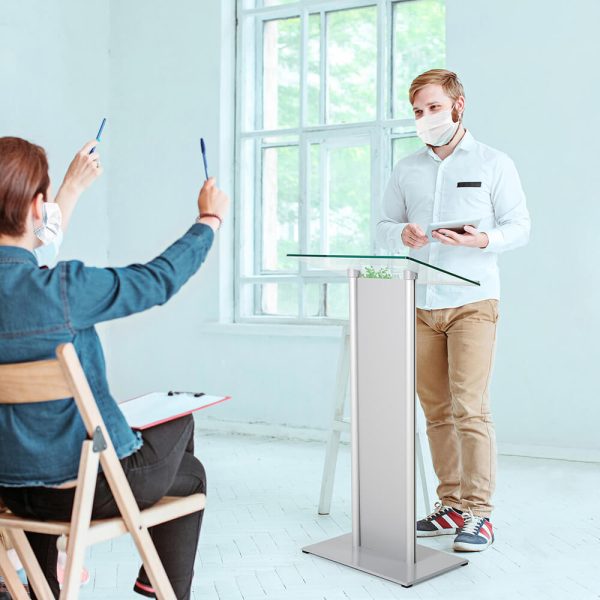 Man giving a presentation from a podium to a group of eager peers