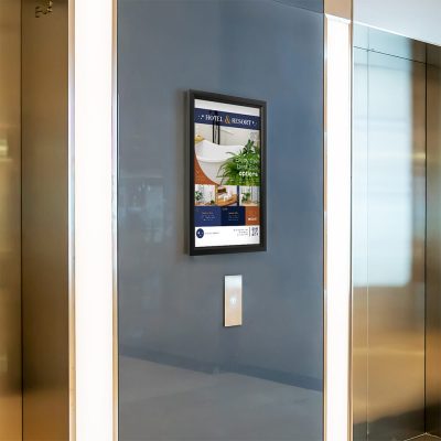 A slide in frame poster in between two elevators in the hallway