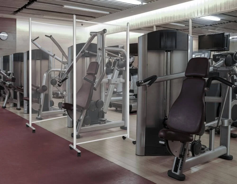 Clear Wall Separator with wheels separating workout equipment in a gym