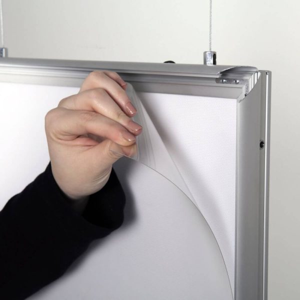 A woman showing the protective layer that goes over your poster in the LED Light Snap Poster Frame