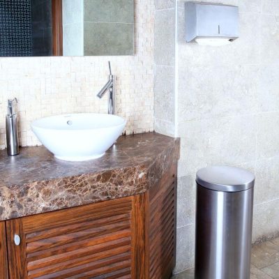 Bathroom Sink with a paper towel holder hanging on the wall above a silver step on trash can